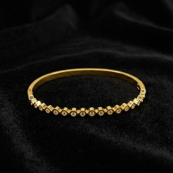 Gold bracelet with small stones on a black fabric background