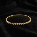 Gold bracelet with small stones on a black fabric background