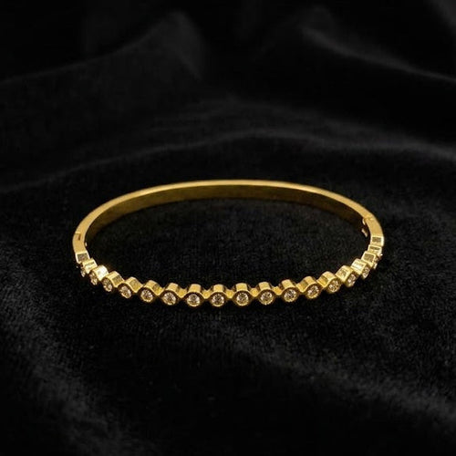 Gold bracelet with small stones on a black fabric background