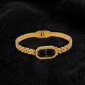 Gold bracelet with a black face on a dark textured background