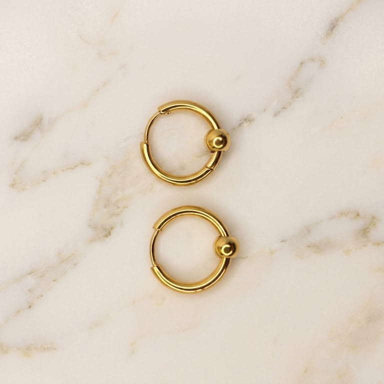 Pair of gold hoop earrings on a marble surface
